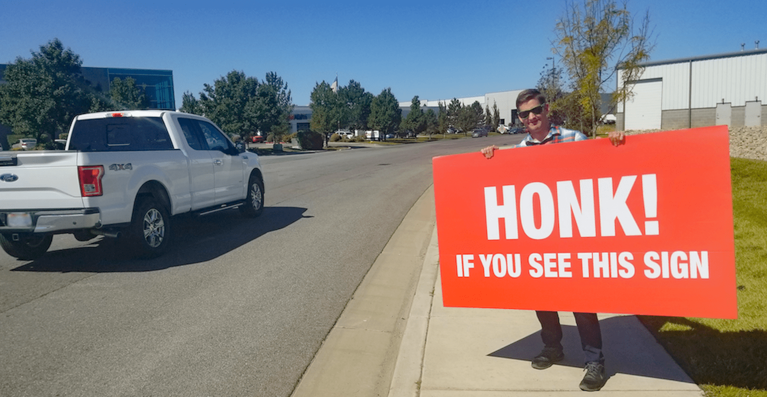 Man holding sign on roadside.