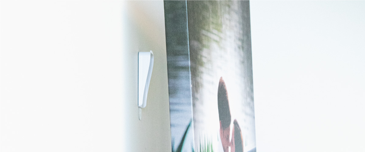 Command® canvas picture hanger on wall with canvas print raised from wall.