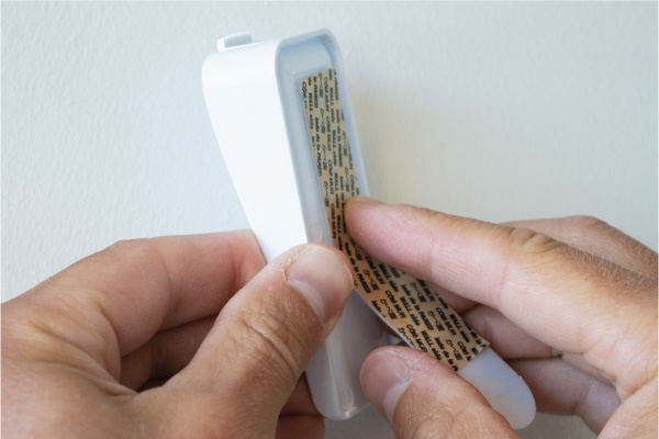 Placing 3M Command Strip® on Canvas Picture Hanger.