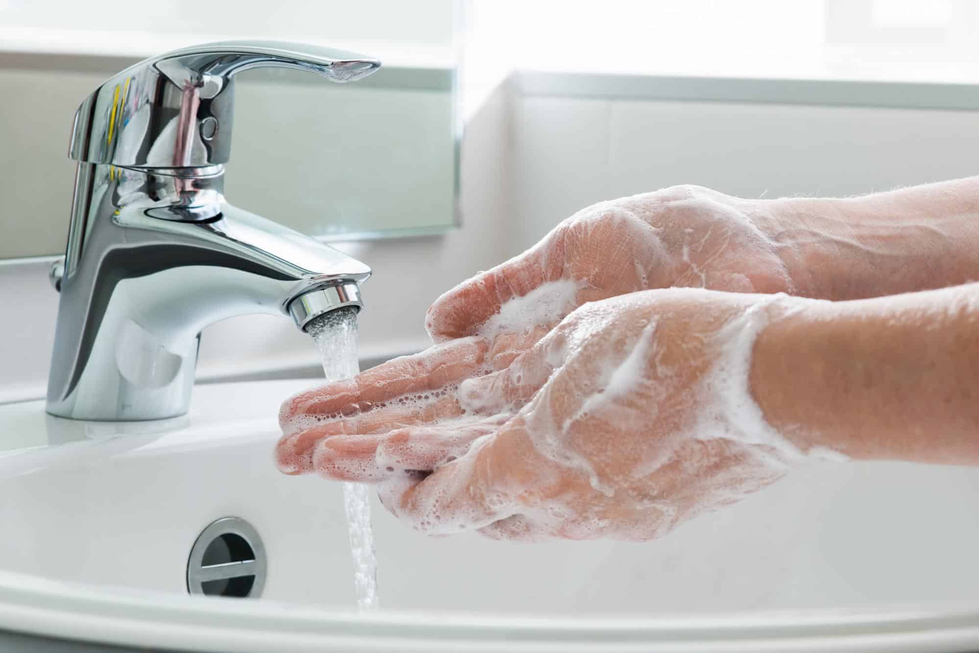 Washing hands with soap and water at bathroom sink