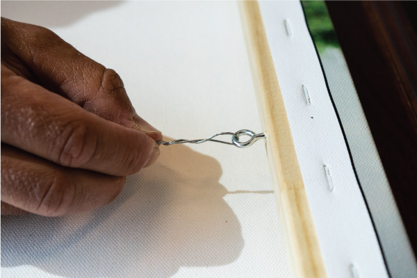Close up view of wire and screw eye attached to canvas print frame.